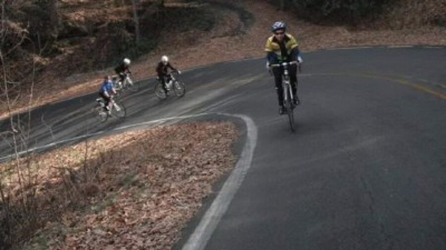 group of cyclist riding on curved mauntain roud