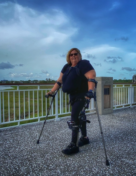 Sandy Hanebrink walking along a pier in her Phoenix exoskeleton